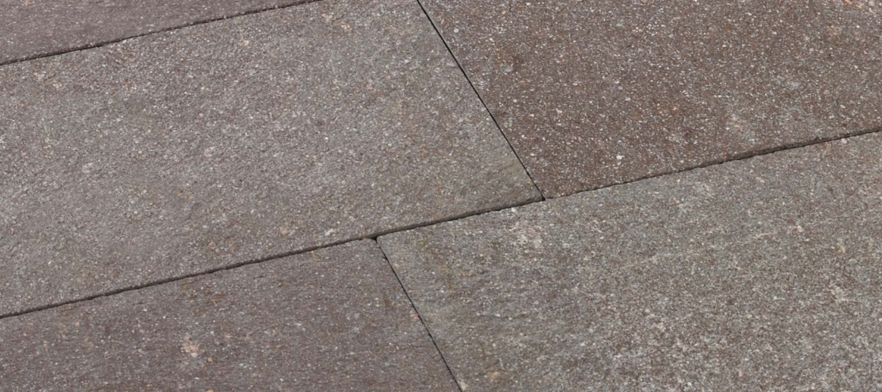 Detailaufnahme von Porphyrplatten in warmen Braun- und Grautönen mit natürlicher Oberfläche