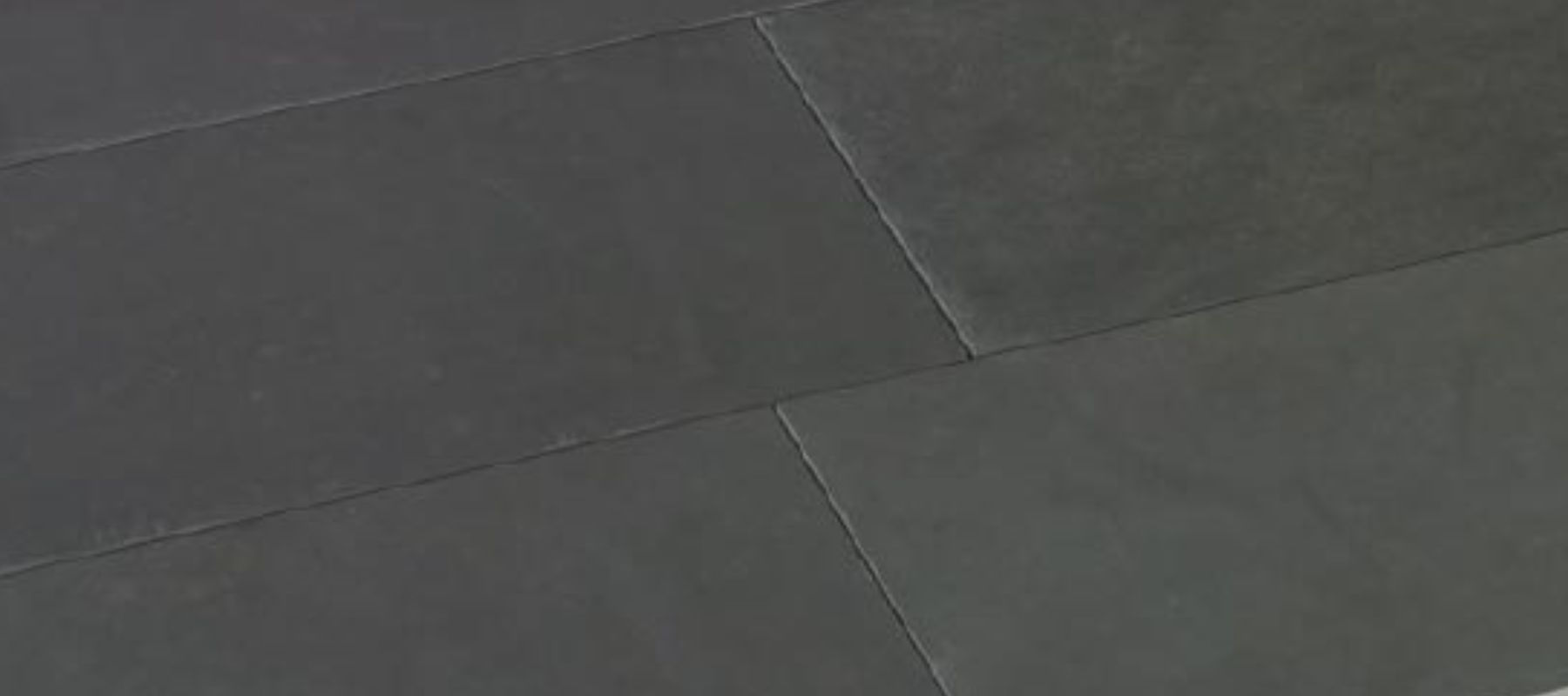Nahaufnahme dunkler Schieferplatten mit glatter, leicht strukturierter Oberfläche.