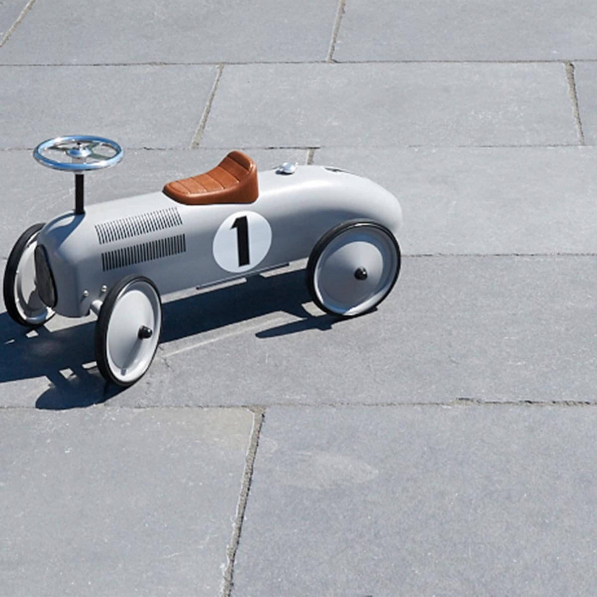 raue Kalksteinplatten auf einer Terrasse mit einem silbernen Spielzeugauto im Retrodesign.